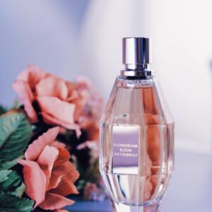 Perfume bottle surrounded by pink roses, showcasing elegance and fragrance.